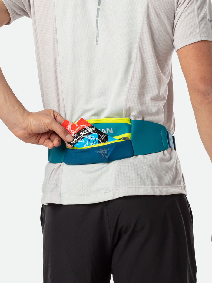 color:Storm Green/Finish Lime||seo:Nathan 5K Waist Running Belt - Storm Green/Finish Lime - On Model - Runner Pulling Out Glukos Energy Gel From Storage Pocket