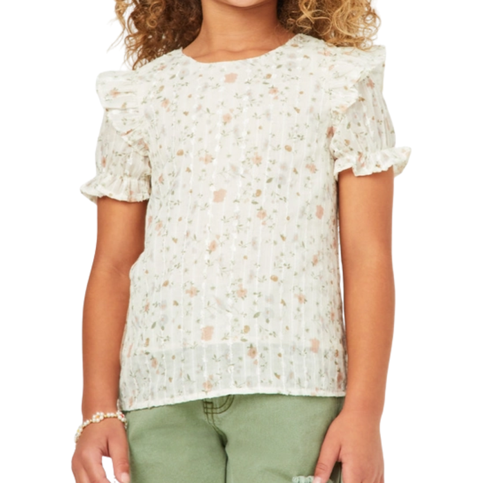 Girl wearing a light floral ruffle sleeve top with pastel flowers and textured fabric paired with green pants.