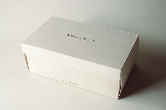 Minimalist beige shoe box with MORAL CODE text on lid, premium footwear packaging