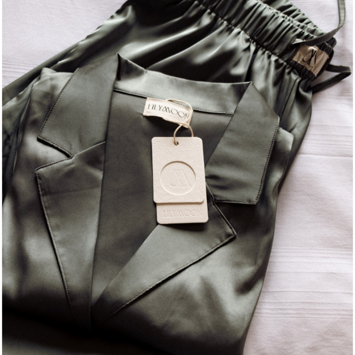 Green satin pyjama set with a tag on a light coloured bed