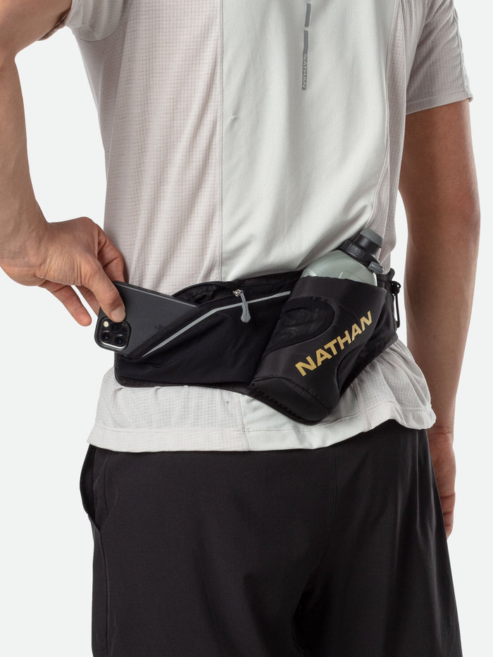 color:Black/Gold||seo:Nathan Peak Hydration Waist Pack - Black/Gold - On Model - Runner Pulling Cell Phone Out of Pack