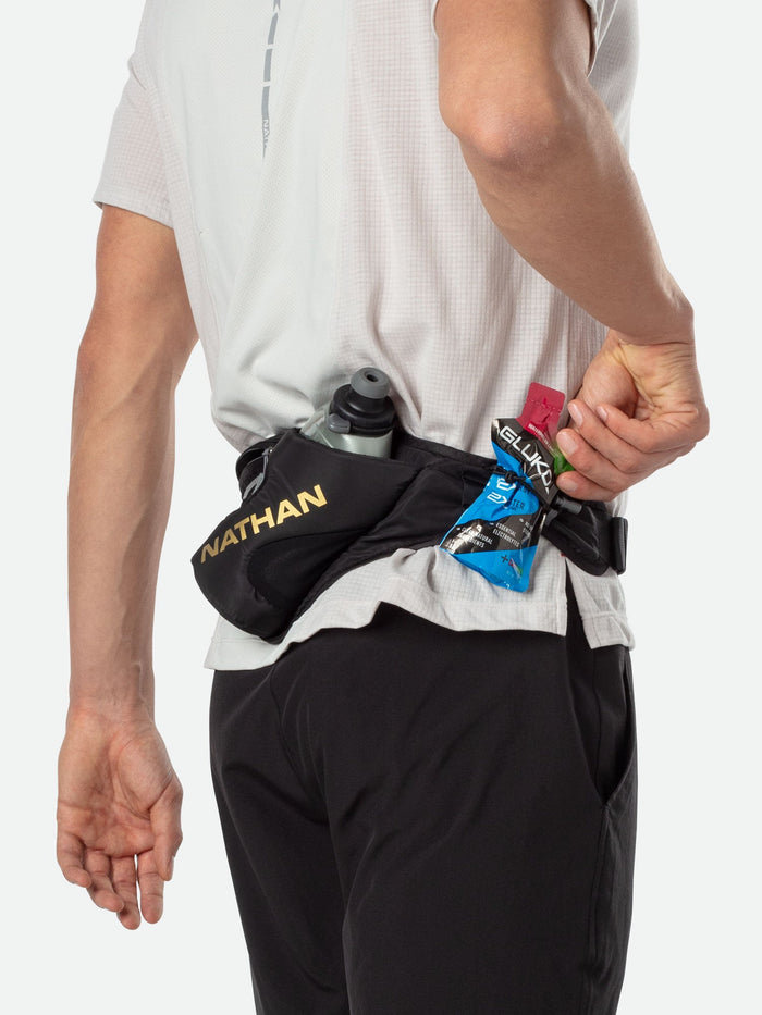 color:Black/Gold||seo:Nathan Peak Hydration Waist Pack - Black/Gold - On Model - Shock Cord System Holding Glukos Energy Gels