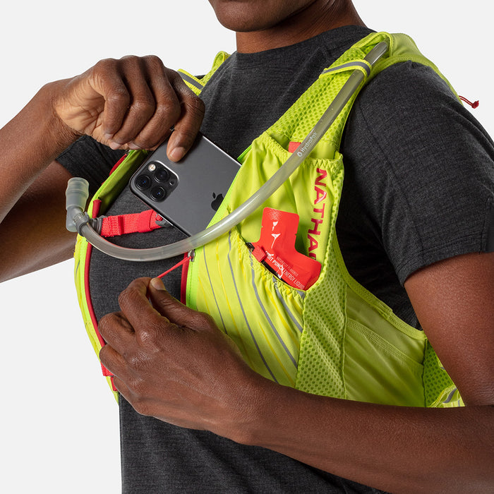 color:Finish Lime/Hibiscus||seo:Nathan Pinnacle 12 Liter Women's Hydration Race Vest - Finish Lime/Hibiscus Red - Female Runner Pulling Cell Phone From Front Pocket