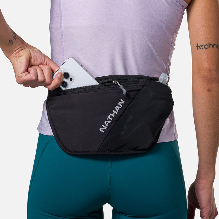 color:Black/Reflective Silver||seo:Nathan Pinnacle FeatherLite Unisex Hydration Waist Belt - Black/Reflective Silver - Model Pulling iPhone from Zippered Pocket
