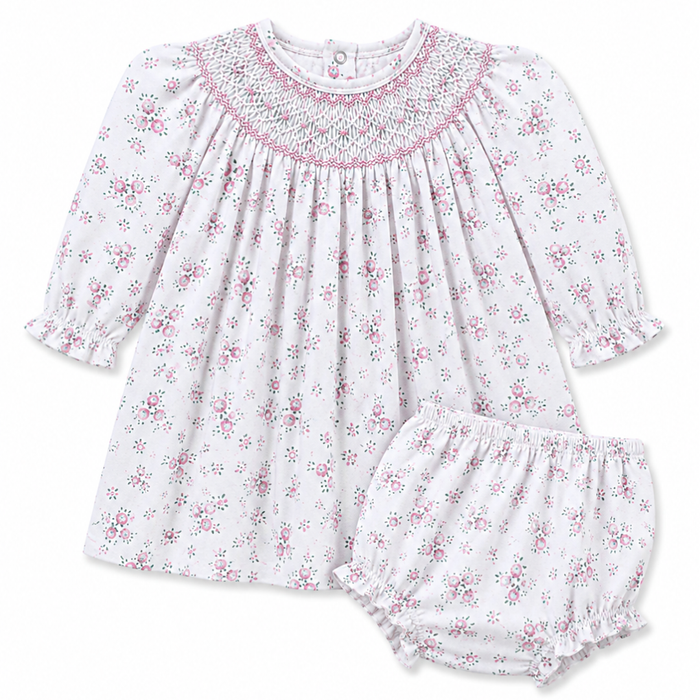 Girls white knit floral bishop dress with pink rosebud print, hand-smocked neckline, and long puff sleeves with ruffle cuffs.