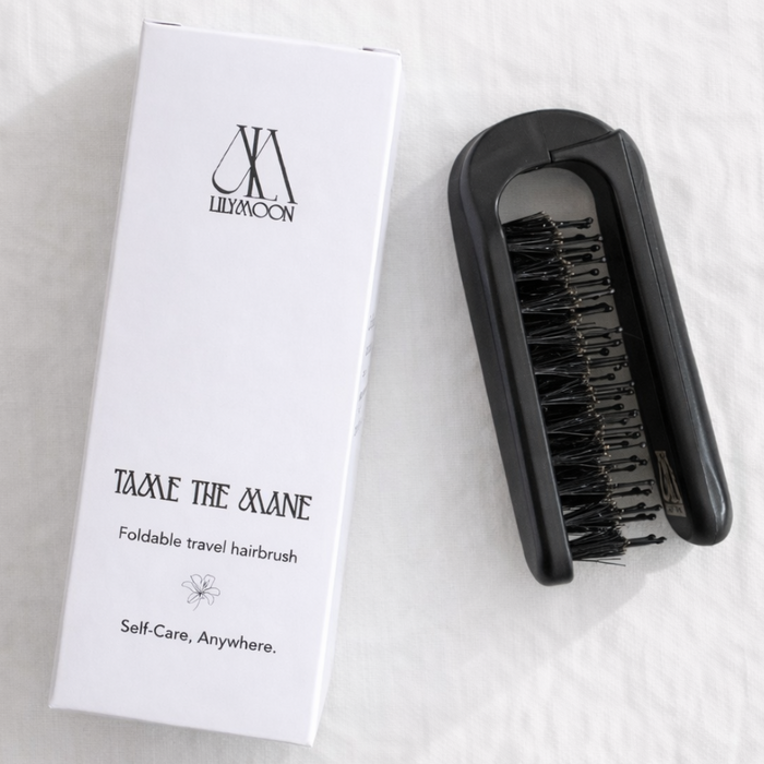 Black travel hairbrush with packaging on a white background