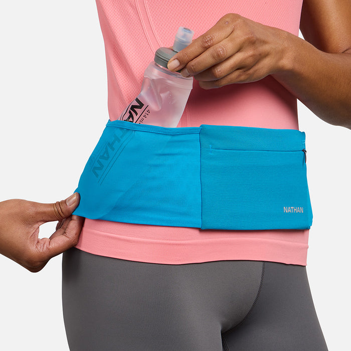 color:Electric Blue/Reflective Silver||seo: Nathan Zipster Max Training Waist Belt - Electric Blue/Reflective Silver - Model Pulling 414ml Hydration Flask Out of Side Storage Pocket
